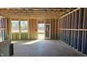 Partially completed living room showcasing exposed framing, windows, and doorway overlooking outdoor greenery at 3858 Well Fleet Drive, Willow Springs, NC 27592