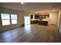A spacious living room with wood floors, large windows, and an open floor plan that includes the kitchen at 60 Calabria Ct, Franklinton, NC 27525