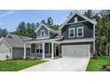 Charming two-story home featuring a two-car garage, gray siding, stone accents, and a well-manicured lawn at 7537 Percussion Dr, Apex, NC 27539