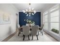 Sophisticated dining area with a unique light fixture, comfortable seating, and a vibrant blue accent wall at 7813 Ailesbury Rd, Wake Forest, NC 27587