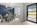 An elegant dining room featuring a modern chandelier, stylish chairs, and a blue accent wall at 7813 Ailesbury Rd, Wake Forest, NC 27587