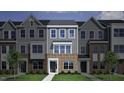 Close-up of townhome with a brick facade, gray siding, large windows, and a welcoming front door at 308 Chesapeak Commons St # 145, Garner, NC 27529