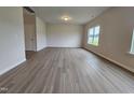 Open-concept living room with wood-look flooring, neutral paint, natural light from a window, and a doorway at 120 Vili Dr, Broadway, NC 27505