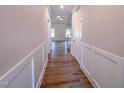 Hallway with wood-look floors and wainscoting, leading to various rooms in the home and a staircase at 403 Duncan Creek Rd # 131, Lillington, NC 27546