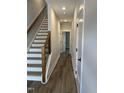 Inviting hallway featuring hardwood floors, white trim, and modern staircase design at 704 Portia Way, Homesite 15, Morrisville, NC 27560