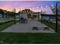 Twilight view of a community pavilion with string lights, picnic tables, and space for neighborhood gatherings at 303 Chesapeake Commons St # 99, Garner, NC 27529