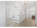 Bright hallway featuring hardwood floors, white trim, and French doors leading to a room at 55 New Liberty Dr, Youngsville, NC 27596