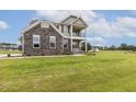 Attractive two-story home with gray siding, stone accents, and a welcoming double stacked front porch at 85 Kissington Way, Benson, NC 27504