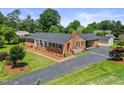 An eye-level aerial showcases the brick home, attached carport and workshop, and the long driveway at 127 Fairfield Cir, Dunn, NC 28334