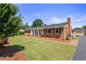 A charming ranch home with manicured lawn, mature landscaping, and an inviting rocking chair front porch at 127 Fairfield Cir, Dunn, NC 28334