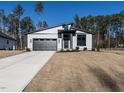 Modern home features a striking gray exterior, complemented by a sleek garage door and manicured landscaping at 145 Ottawa Dr, Louisburg, NC 27549