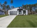 A modern home with a gray garage door and vibrant green lawn at 145 Ottawa Dr, Louisburg, NC 27549