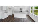 Bright white kitchen features a central island with granite countertops, stainless steel appliances, and hardwood floors at 630 Contento Ct, Sanford, NC 27330