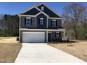 Two-story home boasts a large driveway, attached garage, and a mix of gray and blue siding at 163 Vili Dr, Broadway, NC 27505