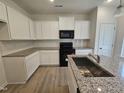 Modern kitchen features granite countertops, stainless steel sink in island, subway tile backsplash, and black appliances at 163 Vili Dr, Broadway, NC 27505