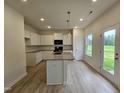 Contemporary kitchen boasts white cabinetry, granite countertops, stainless sink in island, black appliances, and wood flooring at 163 Vili Dr, Broadway, NC 27505