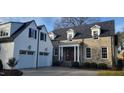 A charming two-story home with stone and white brick exterior, a three-car garage and manicured lawn at 1307 Mayfair Rd, Raleigh, NC 27608