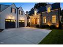 Exterior shot of stone and white house with black garage doors, driveway, and well-kept lawn at 1307 Mayfair Rd, Raleigh, NC 27608