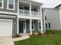 A close-up of the front facade featuring a covered porch, gray siding, and manicured landscaping at 310 N Maple Walk # 236, Garner, NC 27529