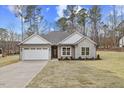 House exterior featuring stone and siding, a two-car garage, and landscaping at 101 Prairie Dog Dr, Louisburg, NC 27549