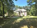 Traditional-style home with a lush lawn, mature trees, and a charming front garden at 109 Springwood Dr, Wake Forest, NC 27587