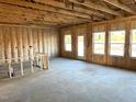 A spacious living room with insulated walls, exposed ceiling beams, concrete flooring and a glass paneled door at 260 Olivia Crossing Ct # 9, Four Oaks, NC 27524