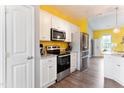 Bright kitchen features stainless steel appliances, white cabinetry and yellow accent wall at 58 Northview Dr, Middlesex, NC 27557