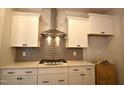 Close-up view of the kitchen with stainless steel range hood, gas range, white cabinets, and tile backsplash at 70 Accord Dr, Youngsville, NC 27596