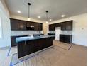 Bright and airy kitchen featuring dark cabinets, an island with sink, and modern pendant lighting at 107 Pretty Run Branch Ln, Wendell, NC 27591