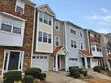 Three-story townhome community with stone and siding, two-car garages, and landscaping at 1527 Haywards Heath Ln, Apex, NC 27502