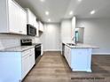 Modern kitchen with white cabinets, granite counters, and stainless steel appliances at 313 Springtooth Dr, Zebulon, NC 27597