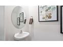 Small half bathroom with pedestal sink and oval mirror at 446 Belgian Red Way, Wake Forest, NC 27587