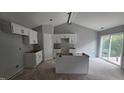 Bright kitchen with white cabinetry, island, and sliding glass doors to the backyard at 121 Tanglewood Dr # 8-J, Louisburg, NC 27549