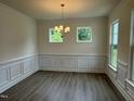 Bright dining room featuring elegant wainscoting, modern lighting, and beautiful wood flooring at 129 Stallion Way, Benson, NC 27504