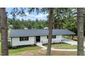White ranch home with a dark gray roof, nestled among trees at 889 Burlington Rd, Roxboro, NC 27573