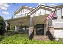 Inviting craftsman-style home with a welcoming front porch, brick accents, and American flag at 108 Cross Oaks Pl, Holly Springs, NC 27540