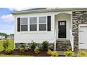 Charming home entrance featuring stone accents, black shutters, and well-maintained landscaping at 155 Scenic Rock Dr, Youngsville, NC 27596