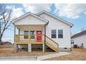 Single Gathering home boasts a charming front porch and white siding, complete with well-maintained landscaping at 825 Graham St, Burlington, NC 27217