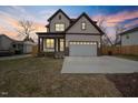 Charming two-story home featuring light siding, dark trim, covered porch, and an attached two-car garage at 112 1St St, Oxford, NC 27565