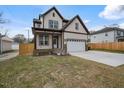 Charming two-story home featuring light siding, dark trim, covered porch, and an attached two-car garage at 112 1St St, Oxford, NC 27565