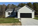 Newly constructed home with a gray exterior, black garage door, and a well-manicured lawn at 120 Magnolia Run Way, Benson, NC 27504