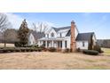 Elegant white two-story house with a brick chimney, manicured shrubs, and a inviting front porch at 1200 Spring Valley Lake Rd, Henderson, NC 27536