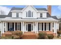 Charming front porch with brick flooring, classic columns, dark shutters, and a comfortable porch swing at 1200 Spring Valley Lake Rd, Henderson, NC 27536