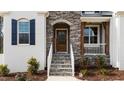Close-up of a charming home entrance featuring a welcoming wooden front door and stone steps at 128 S Clearbrook Ct, Angier, NC 27501
