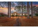 Inviting single-story brick home with a brick path, surrounded by majestic trees and beautiful sunset ambiance at 302 S Pine St, Benson, NC 27504