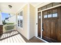 Inviting front porch with wood flooring, a dark wood door with glass panes, and stone pillar bases at 4538 Brighton Ridge Dr, Apex, NC 27539