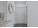 Inviting foyer featuring a round mirror, grey tile flooring and multiple doors leading to various rooms at 105 Fountain Ridge Pl, Holly Springs, NC 27540