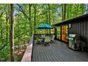 Spacious deck with seating area, umbrella, and grill, overlooking woods at 2100 Tadley Dr, Chapel Hill, NC 27514