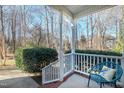 Front porch with white railings, a teal chair, and view of trees at 109 Stoneline Ct, Holly Springs, NC 27540