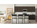 Modern kitchen with dark cabinetry, an island, and stainless steel appliances at 1888 Sweet Gardenia Way, Apex, NC 27502
